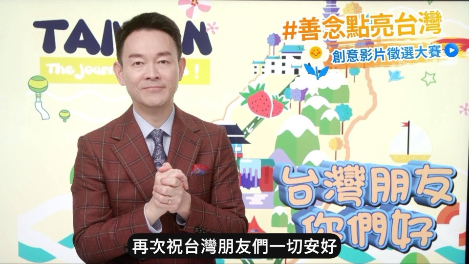善念大使姜光宇在台灣插畫背景前拱手致意